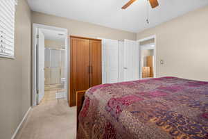 Bedroom featuring light colored carpet, ceiling fan, connected bathroom, and a closet