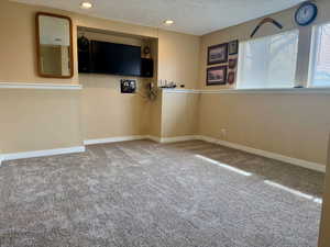 Carpeted empty room featuring a textured ceiling and recessed lighting