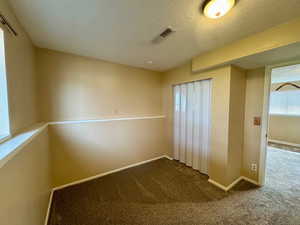 Unfurnished room featuring dark carpet and a textured ceiling