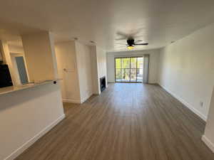 Unfurnished living room featuring light wood finished floors, a ceiling fan, and a fireplace