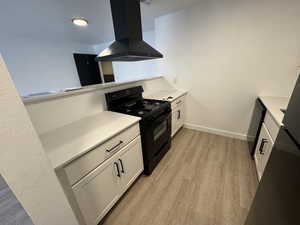 Kitchen with black appliances, white cabinets, light wood-type flooring, and a peninsula