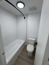 Bathroom featuring wood finished floors and washtub / shower combination