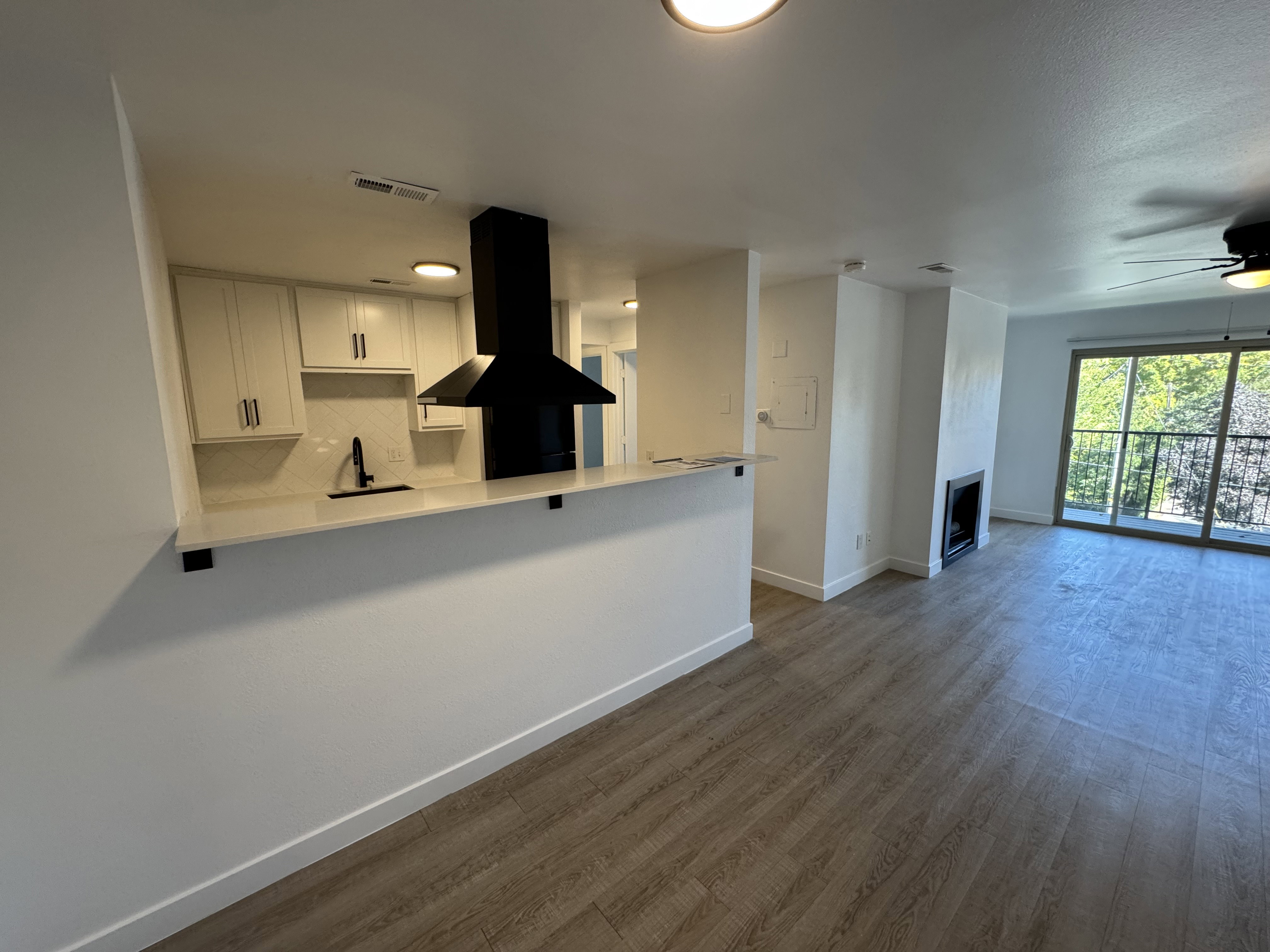 Kitchen featuring white cabinets, extractor fan, ceiling fan, dark wood-type flooring, and backsplash