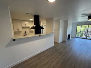 Kitchen featuring white cabinets, extractor fan, ceiling fan, dark wood-type flooring, and backsplash