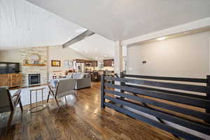 Staircase with wood finished floors, a fireplace, and beamed ceiling