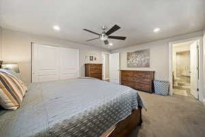 Carpeted bedroom with a closet, ceiling fan, recessed lighting, and ensuite bathroom