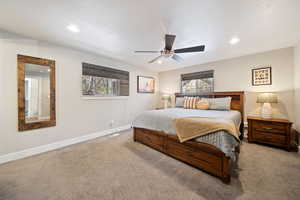 Carpeted bedroom featuring multiple windows, ceiling fan, and recessed lighting