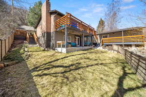 Rear view of property featuring a patio area, a chimney, and a deck