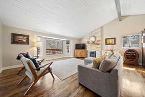 Living area with wood-type flooring, a fireplace, and a high wooden beamed ceiling