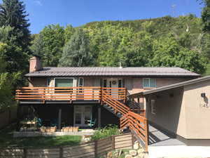 View of front of house featuring brick siding, french doors, a wooden deck, a chimney, and a patio area