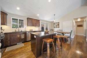 Kitchen with a center island, dark wood finish cabinetry, tasteful backsplash, a breakfast bar, and dark wood finished floors