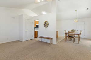 Dining room featuring lofted ceiling, light colored carpet, and ceiling fan