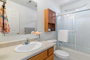 Full bath featuring vanity and bath / shower combo with glass door