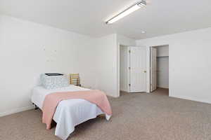 Bedroom with light carpet, a textured ceiling, and a closet