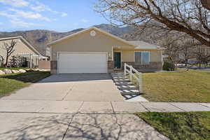 Ranch-style home with brick siding, a mountain view, concrete driveway, and an attached garage