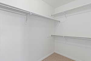 Walk in closet with light colored carpet