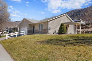 Single story home featuring a mountain view, brick siding, an attached garage, and a front lawn