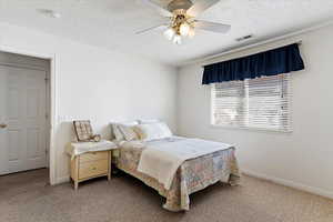 Bedroom with carpet, a textured ceiling, and a ceiling fan