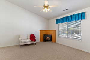 Sitting room featuring carpet flooring, ceiling fan, a lit fireplace, and lofted ceiling