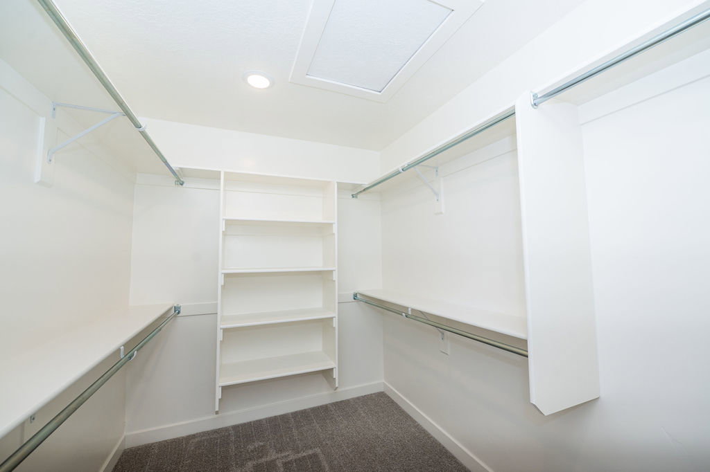 Walk in closet featuring dark colored carpet