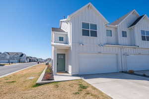 View of front of home featuring board and batten siding, an attached garage, roof with shingles, concrete driveway, and a residential view