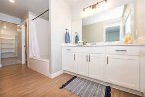 Full bathroom featuring vanity, shower / bath combo, and light wood-style flooring