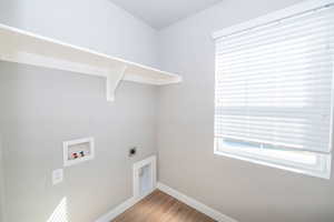 Laundry room with electric dryer hookup, washer hookup, light wood-style floors, and healthy amount of natural light