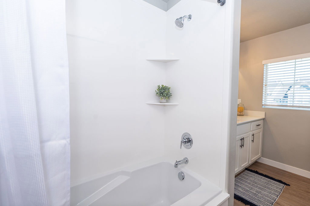Bathroom with shower / bathtub combination with curtain, vanity, and wood finished floors