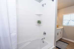 Bathroom with shower / bathtub combination with curtain, vanity, and wood finished floors