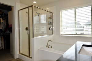 Bathroom featuring a walk in closet, a stall shower, a garden tub, and recessed lighting