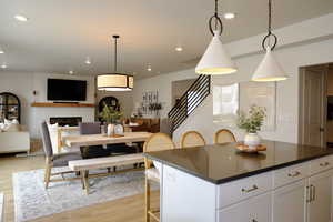 Kitchen with a kitchen breakfast bar, light wood-style floors, a kitchen island, white cabinetry, and open floor plan