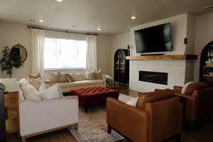 Living room featuring dark wood finished floors, a brick fireplace, and recessed lighting