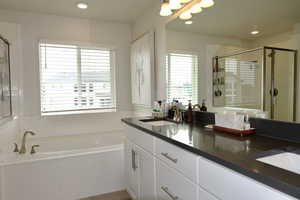 Full bathroom with double vanity, a bath, a shower stall, recessed lighting, and light tile patterned floors