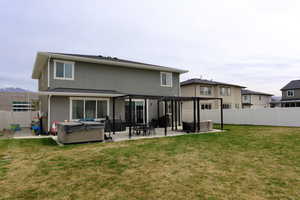 Back of house featuring a fenced backyard, a hot tub, a patio, and stucco siding