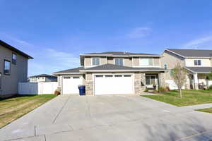 View of front of house featuring an attached garage, driveway, and stone siding