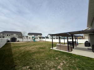 Fenced backyard featuring a residential view, a playground, a patio, a storage unit, and outdoor seating