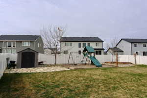 Back of house featuring a patio area, a fenced backyard, a shed, and a playground