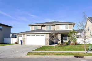 View of front of house with concrete driveway, a garage, stone siding, and a porch