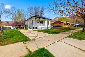 Bungalow featuring a mountain view, driveway, a porch, stucco siding, and a shed