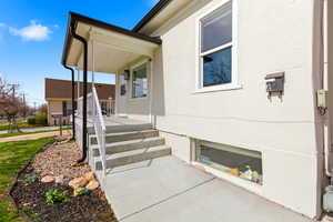 Entrance to property featuring covered porch and stucco siding