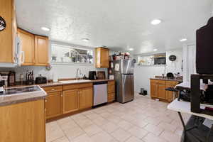 Kitchen with stainless steel appliances, dark countertops, a textured ceiling, recessed lighting, and light tile patterned flooring