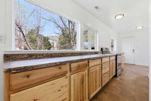 Kitchen with dark countertops, stainless steel range with electric stovetop, and light wood finish cabinets