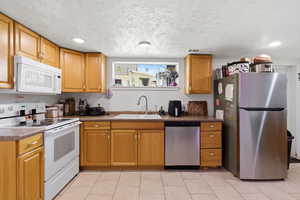 Kitchen with stainless steel appliances, dark countertops, a textured ceiling, recessed lighting, and light tile patterned flooring