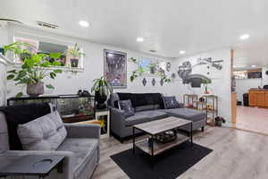 Basement living area featuring light wood-type flooring and recessed lighting