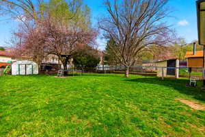Fenced backyard featuring a shed