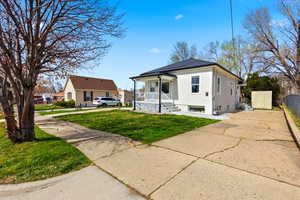 Bungalow with a porch, a front lawn, concrete driveway, and stucco siding