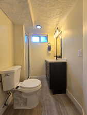 Bathroom with vanity, dark wood-style flooring, a shower stall, and a textured ceiling
