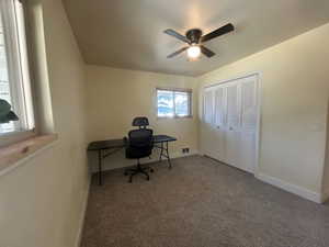 Home office with dark carpet and ceiling fan