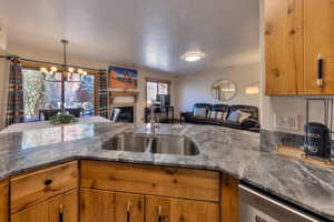 Kitchen with wood finish cabinetry, open floor plan, a tiled fireplace, and a chandelier