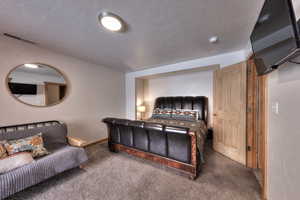 Carpeted bedroom with a textured ceiling and baseboards